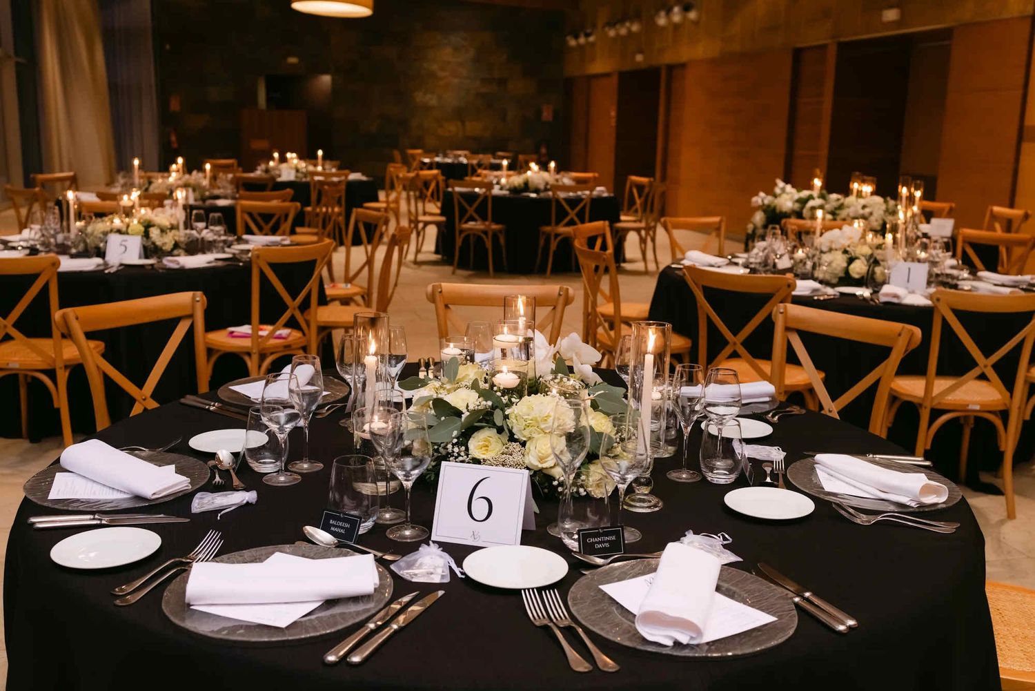 A bold and modern luxury wedding banquet setup at Castell Jalpí featuring round tables with black tablecloths and elegant centerpieces.