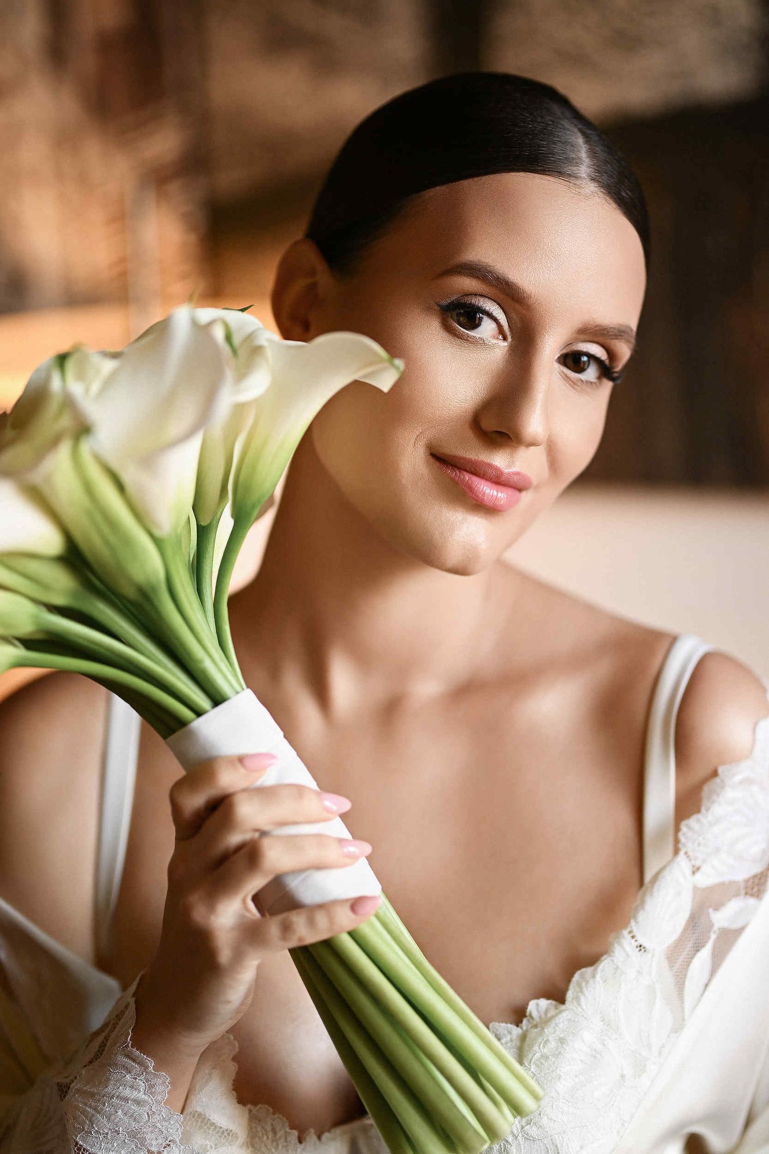 Bride with calla lilies in her boudoir showcasing a final professional makeup look. Elegant bridal beauty services in a Spanish villa.