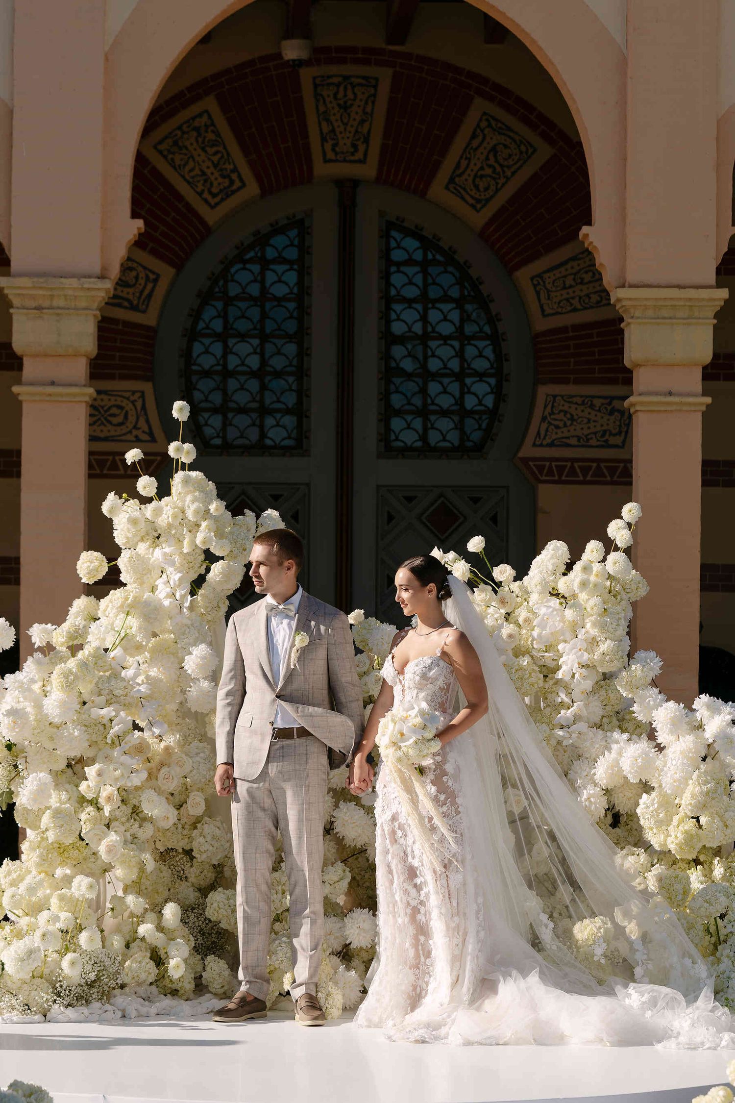 The bride and groom at their wedding ceremony with the majestic Gran Villa Rosa mansion as a backdrop, capturing a romantic moment