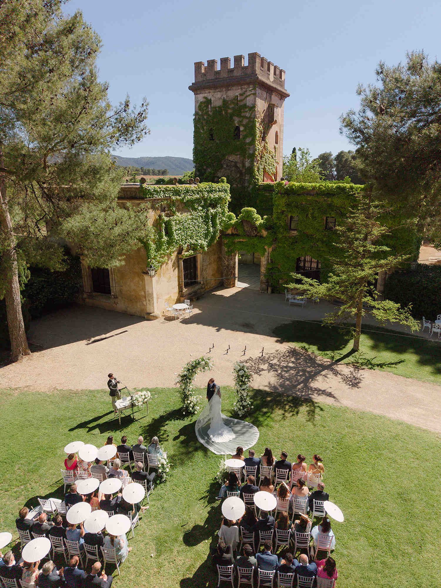 Drone view of the wedding ceremony at Finca Torrefiel. Bride with a long dress train and flowing veil standing with the groom.