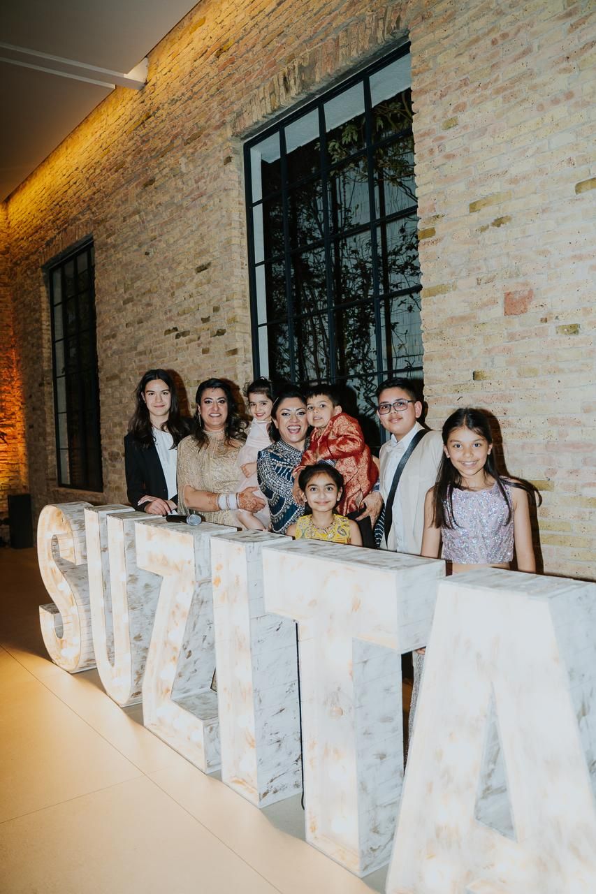 A large group photo of happy guests celebrating at the Indian lesbian wedding reception.