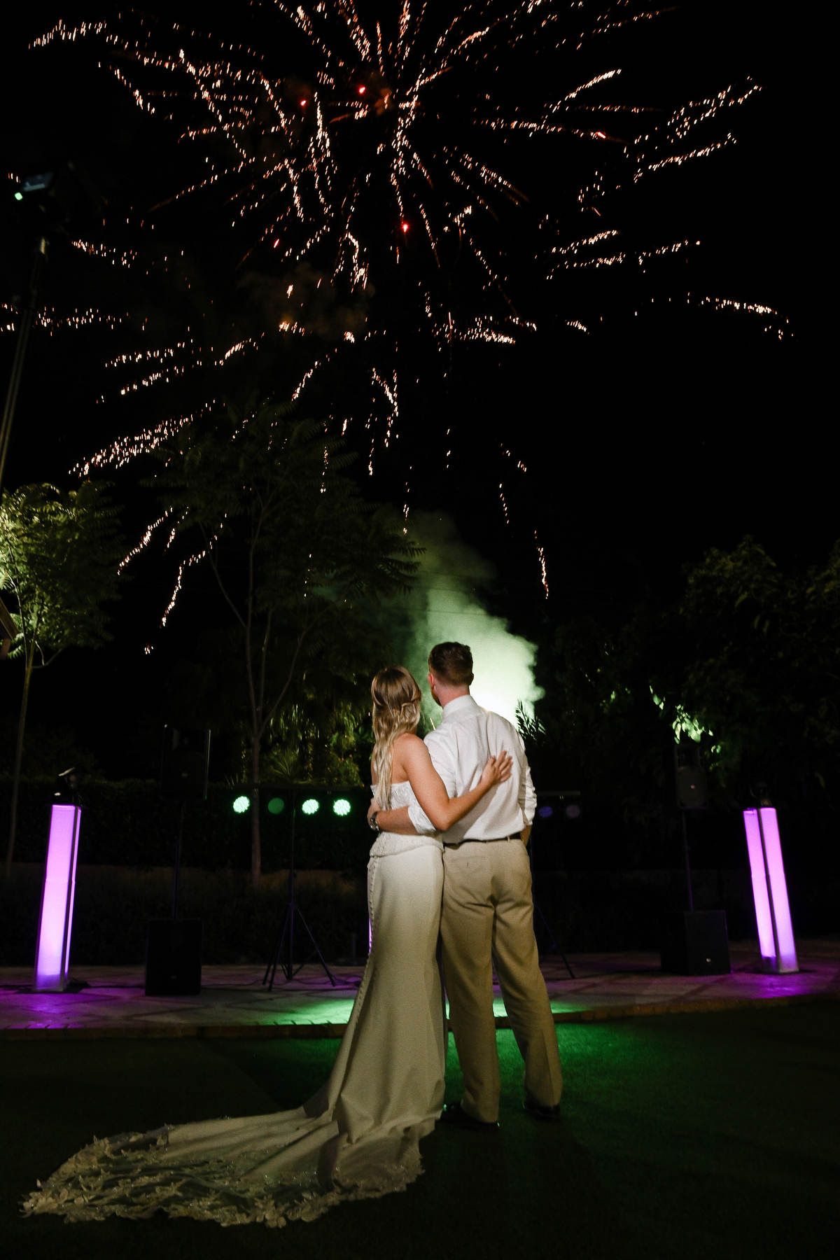 Back view of a couple watching grand wedding fireworks at Villa Delia. The bridal updo stays perfectly secure until the midnight banquet.
