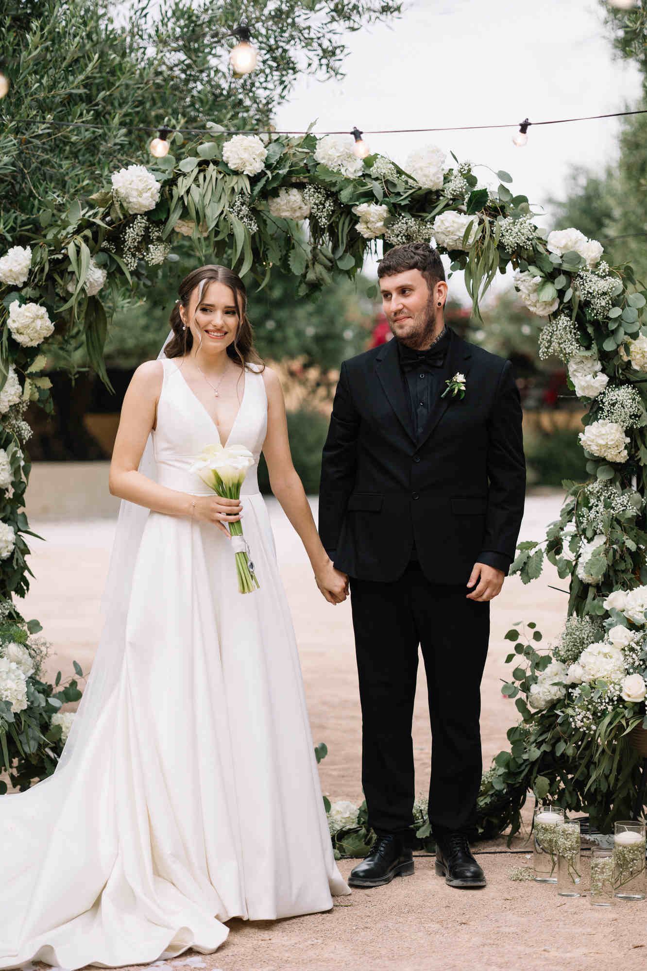 Happy bride and groom smiling during their outdoor wedding ceremony at the rustic Alqueria del Xúquer estate in Valencia.