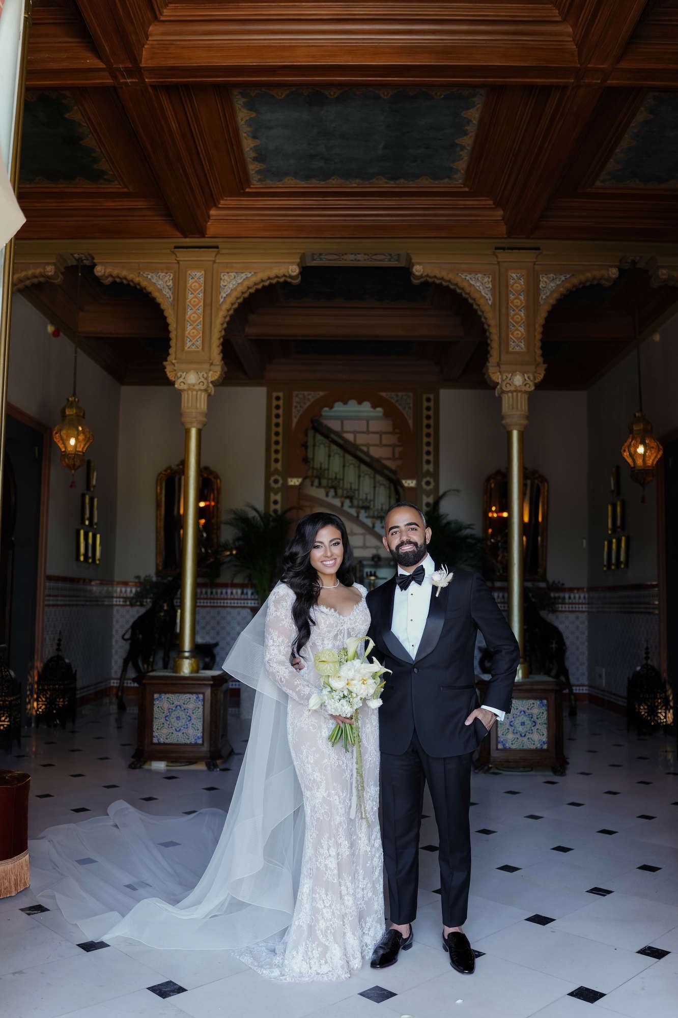 The bride and groom posing in the ornate interior hall of Gran Villa Rosa, showing a sophisticated destination wedding style