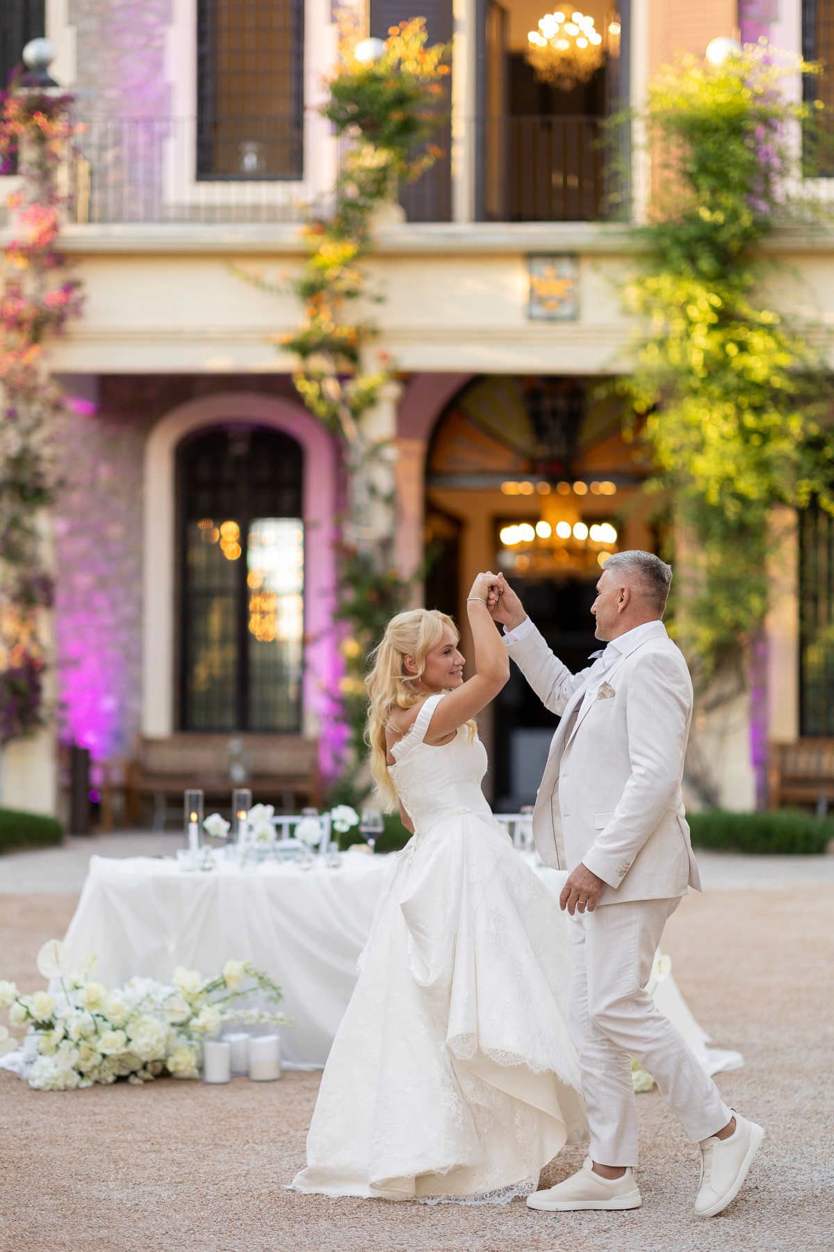 Bride and groom dancing in the courtyard at Finca Marqués de Montemolar; her half-up waves flawless under the chandeliers.