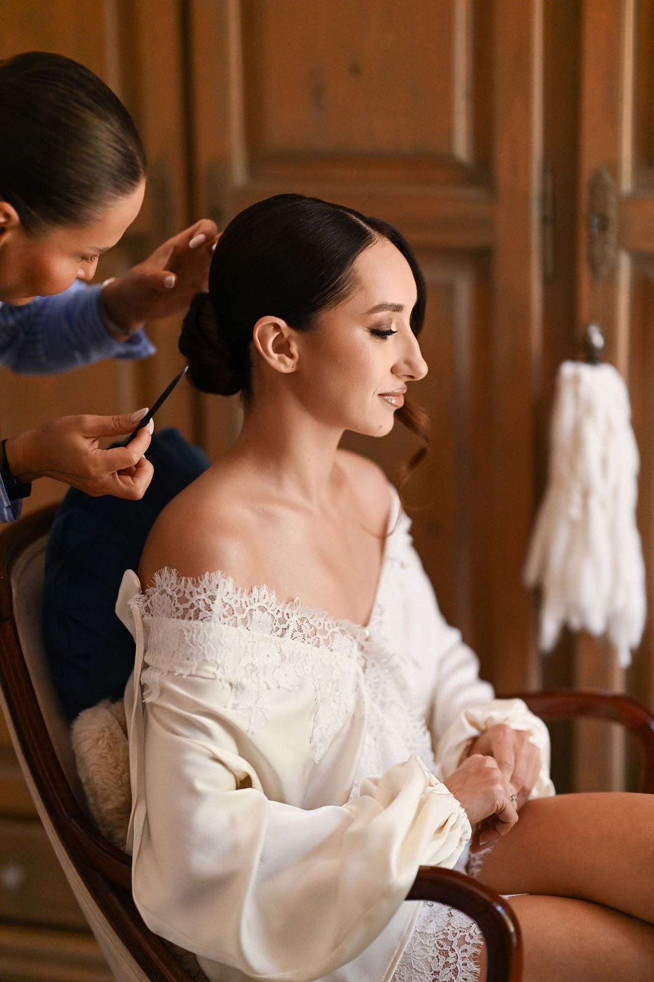 Stylist Anastasia Larionova puts finishing touches on a secure, sleek bridal bun hairstyle for a wedding day at Villa Paula.