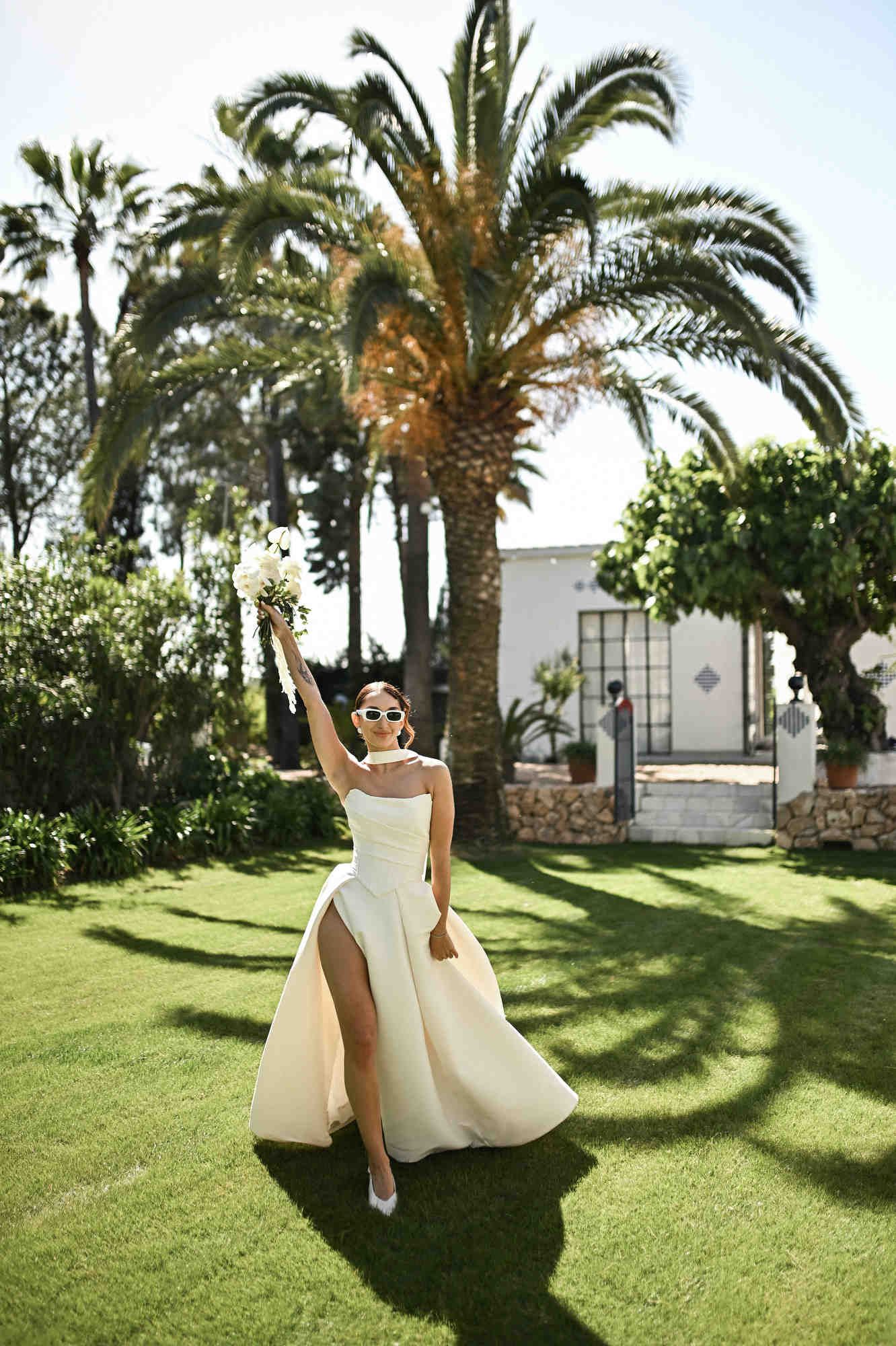 Bride walking and waving her bouquet like a fashion model on a runway across the historic grounds of Villa Paula in Valencia.