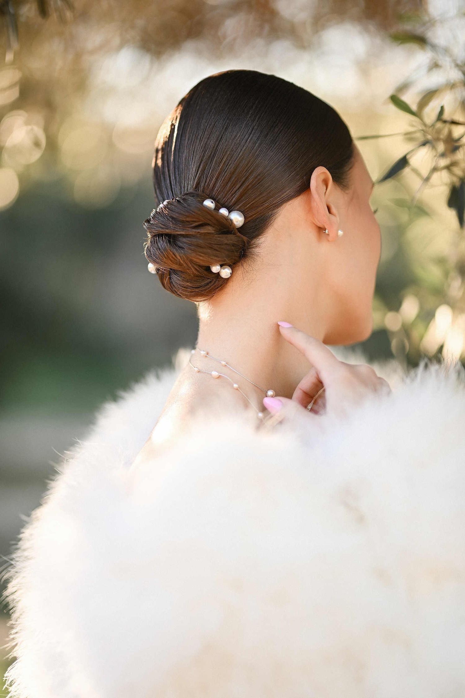 Bride from behind featuring a polished bun hairstyle and elegant fur coat in Spain. Expertly gathered hair for a winter wedding look.