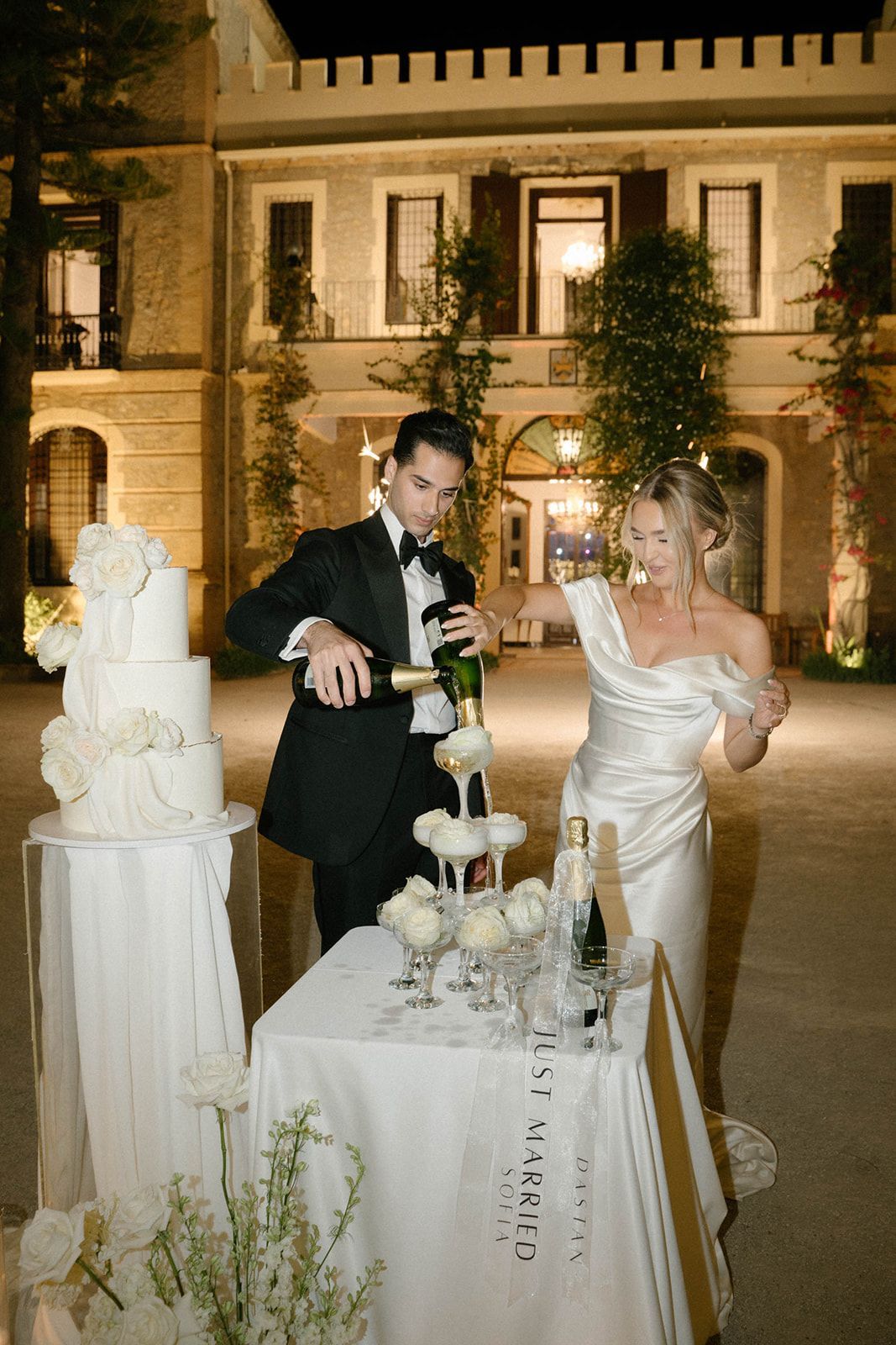 Bride and groom pouring champagne into a glass tower during their wedding reception at the historic Finca Marqués de Montemolar in Altea.