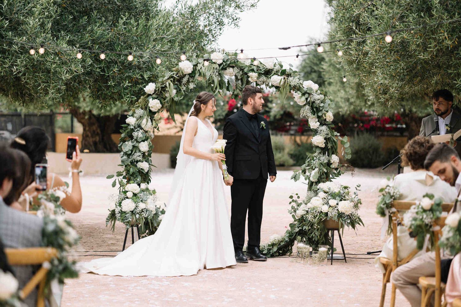 Bride and groom during their wedding ceremony in the olive gardens of Alqueria del Xúquer, Valencia, featuring natural bridal makeup.