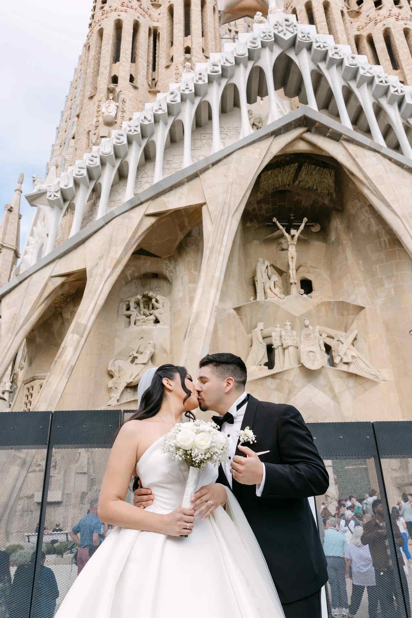 The bride and groom posing with the iconic Sagrada Família in the background after their Barcelona wedding ceremony.