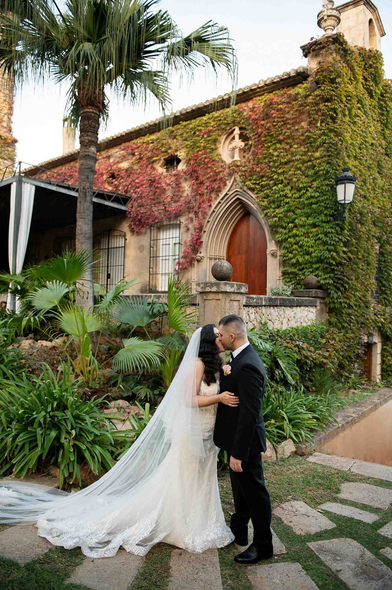 Bride and groom posing under the historic stone arch at Casa Santonja during an elegant autumn wedding photoshoot in the gardens.