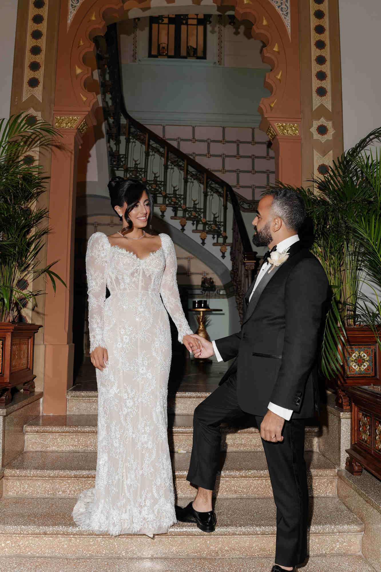 The bride and groom posing on the Gran Villa Rosa stairs, with the bride showcasing a different bridal style for the evening.