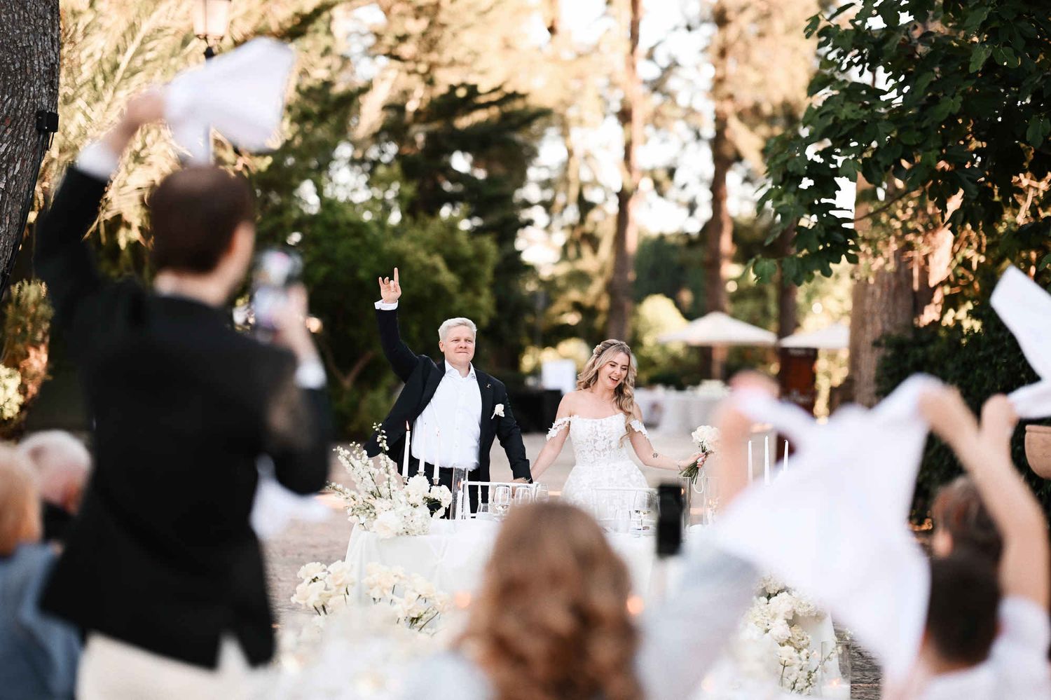 Bride and groom entering their outdoor wedding reception at Finca El Senoret as guests wave handkerchiefs in Alicante