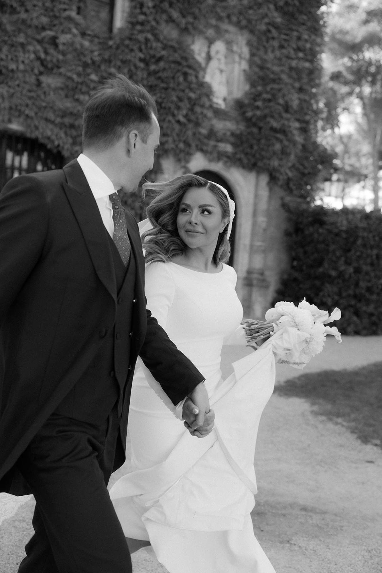 Candid moment of a bride and groom walking through the historic Finca Torrefiel estate. Dynamic outdoor wedding photography.