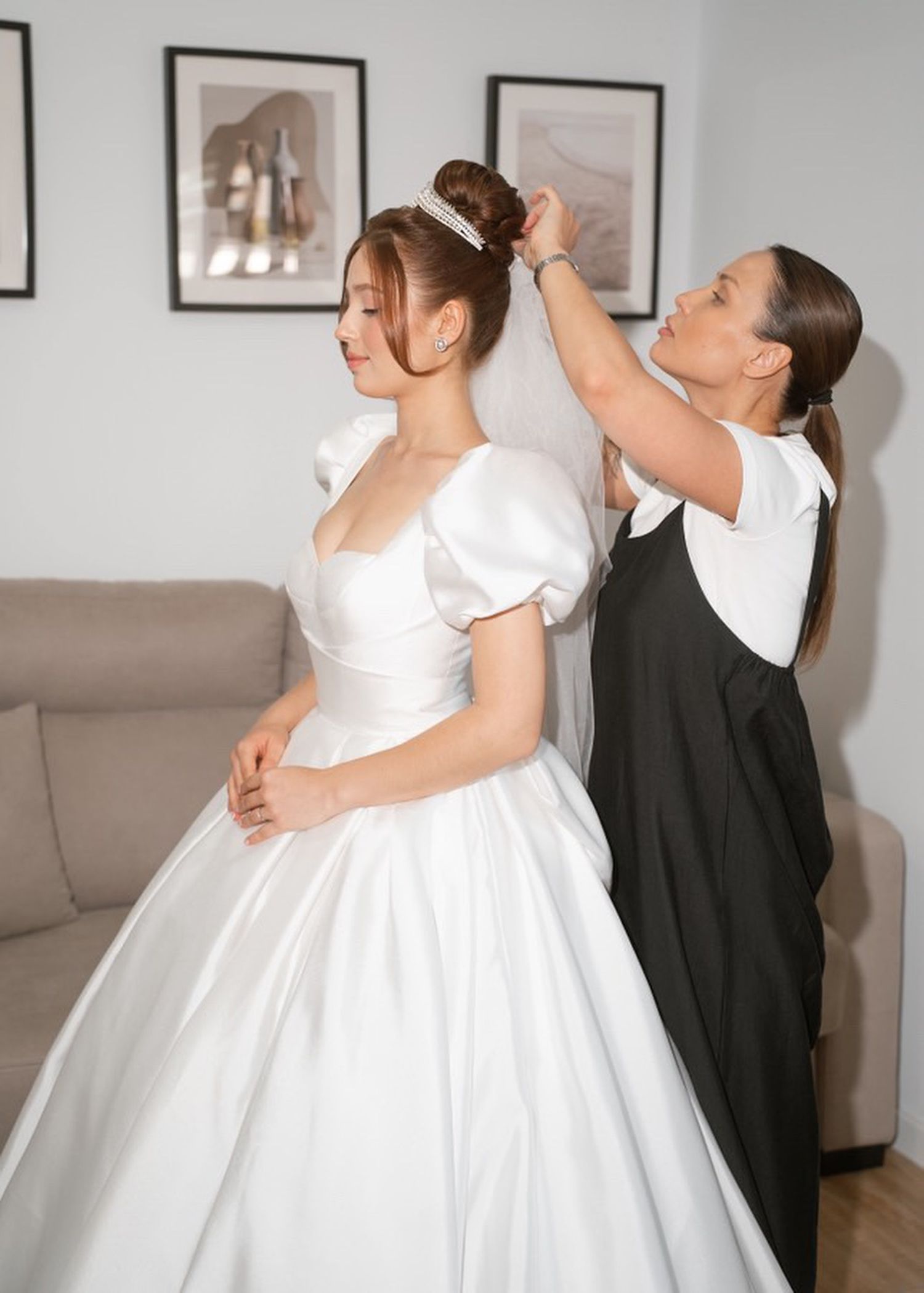 Anastasia Larionova making final preparations on a sleek bridal bun for a destination wedding in a luxury Spanish estate gallery.