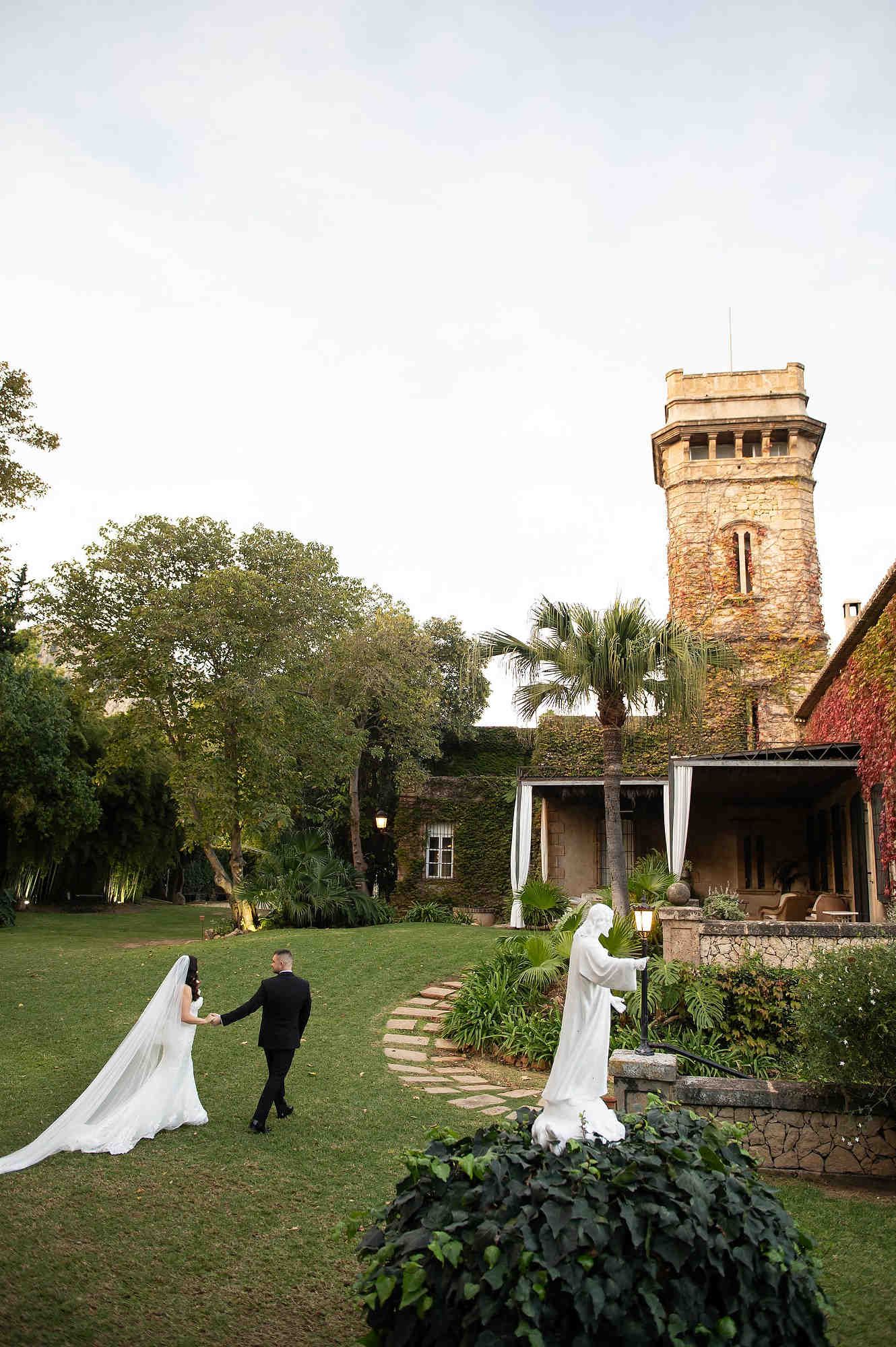 A wide-angle landscape shot of the grand Casa Santonja villa, showing the scale of the estate with the couple.