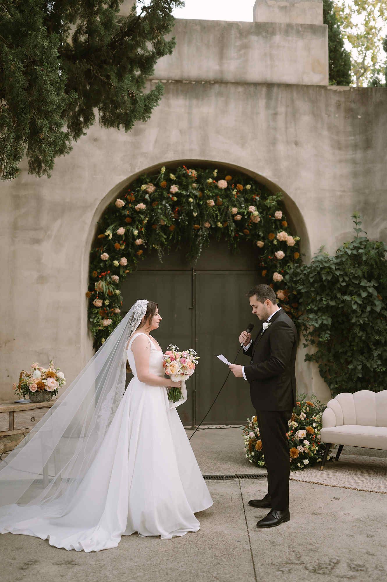 Groom reading his wedding vows in front of a luxury floral arch during a ceremony in Valencia.