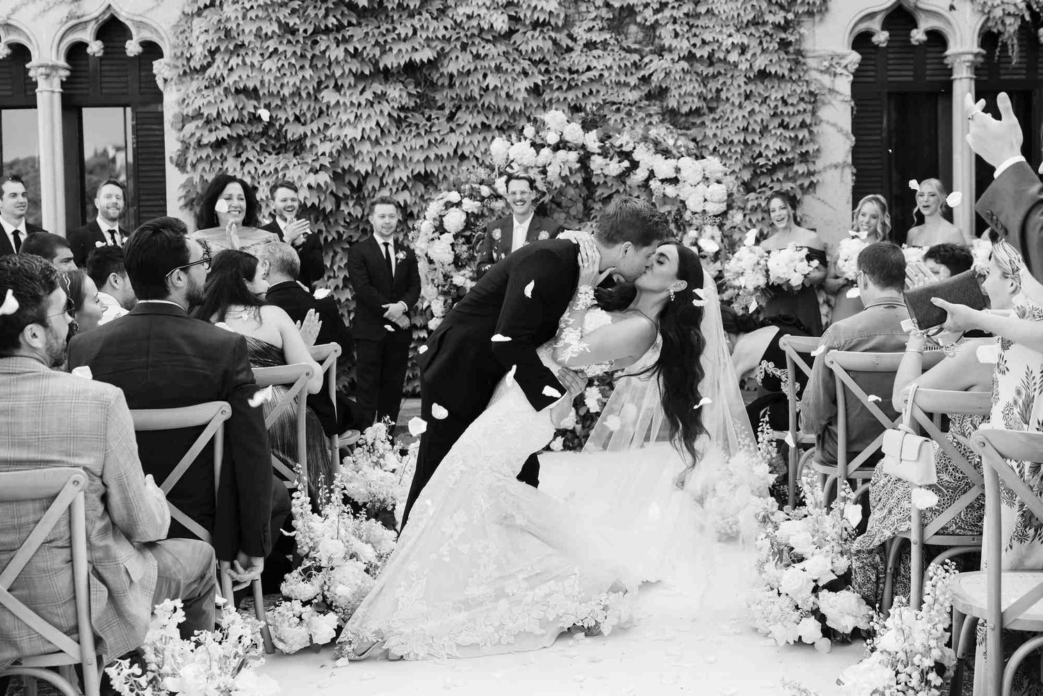 Groom kissing the bride during a romantic wedding ceremony at Castell Jalpí with the historic castle facade in the background, Barcelona.