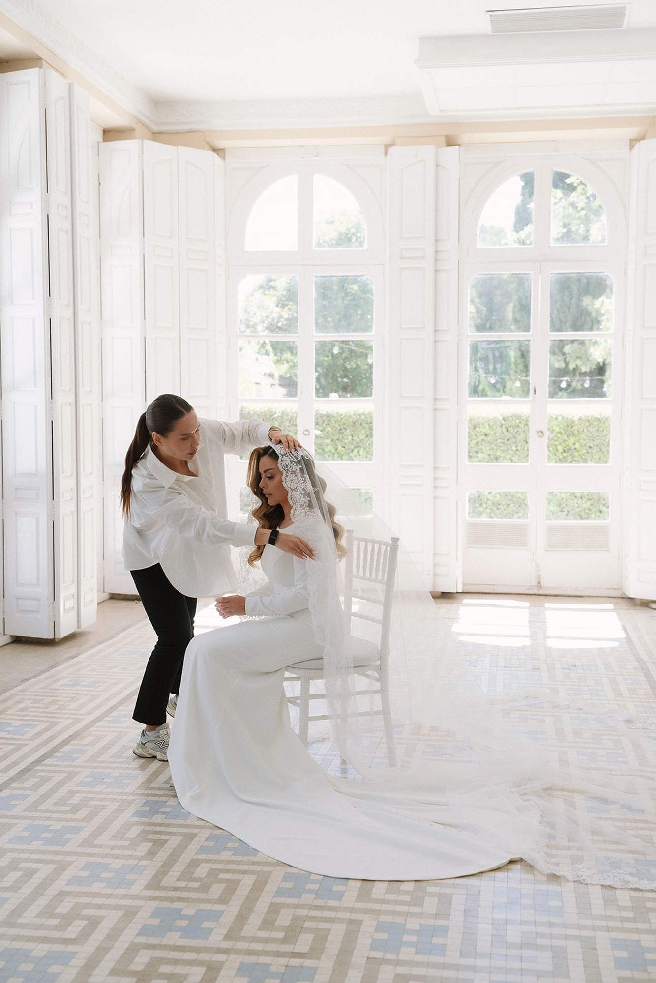 Professional wedding stylist attaching the bridal veil and adding final touches to the wedding makeup and hair at Finca Torrefiel.