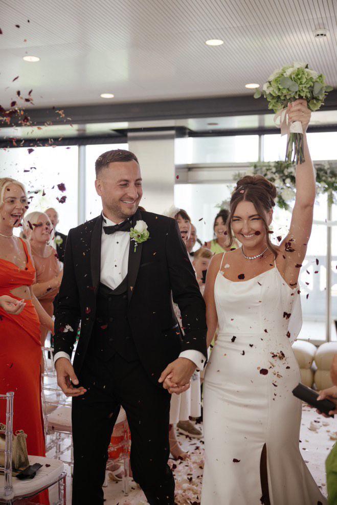 A happy wedding couple being showered by guests during their exit at Hotel Las Arenas, Valencia.