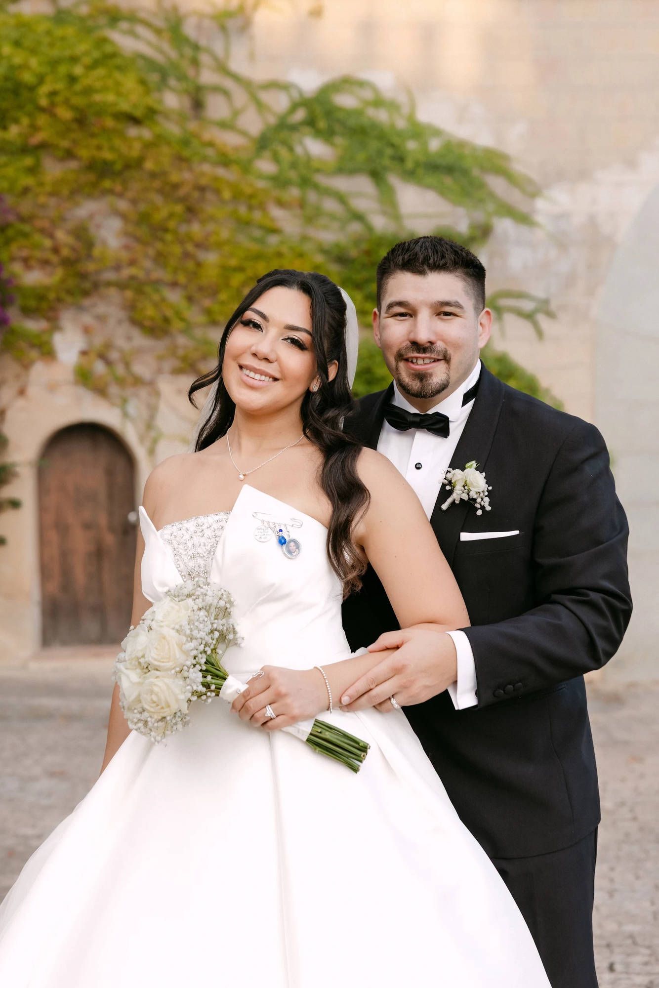 Groom hugging the bride featuring beautiful wavy hair strands. Professional bridal makeup and hair styling for a luxury Spanish wedding.
