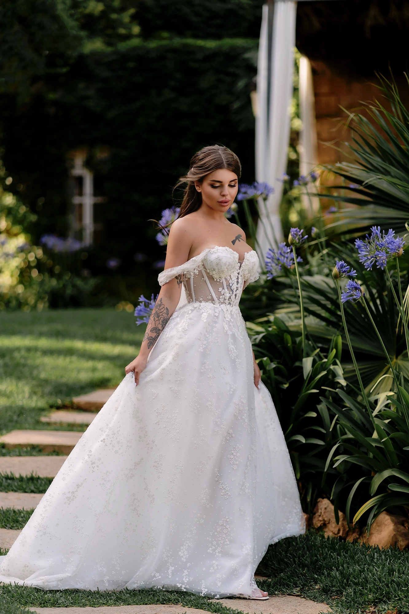 A bride in a sophisticated off-the-shoulder dress walking through the romantic stone courtyard of the Casa Santonja estate.