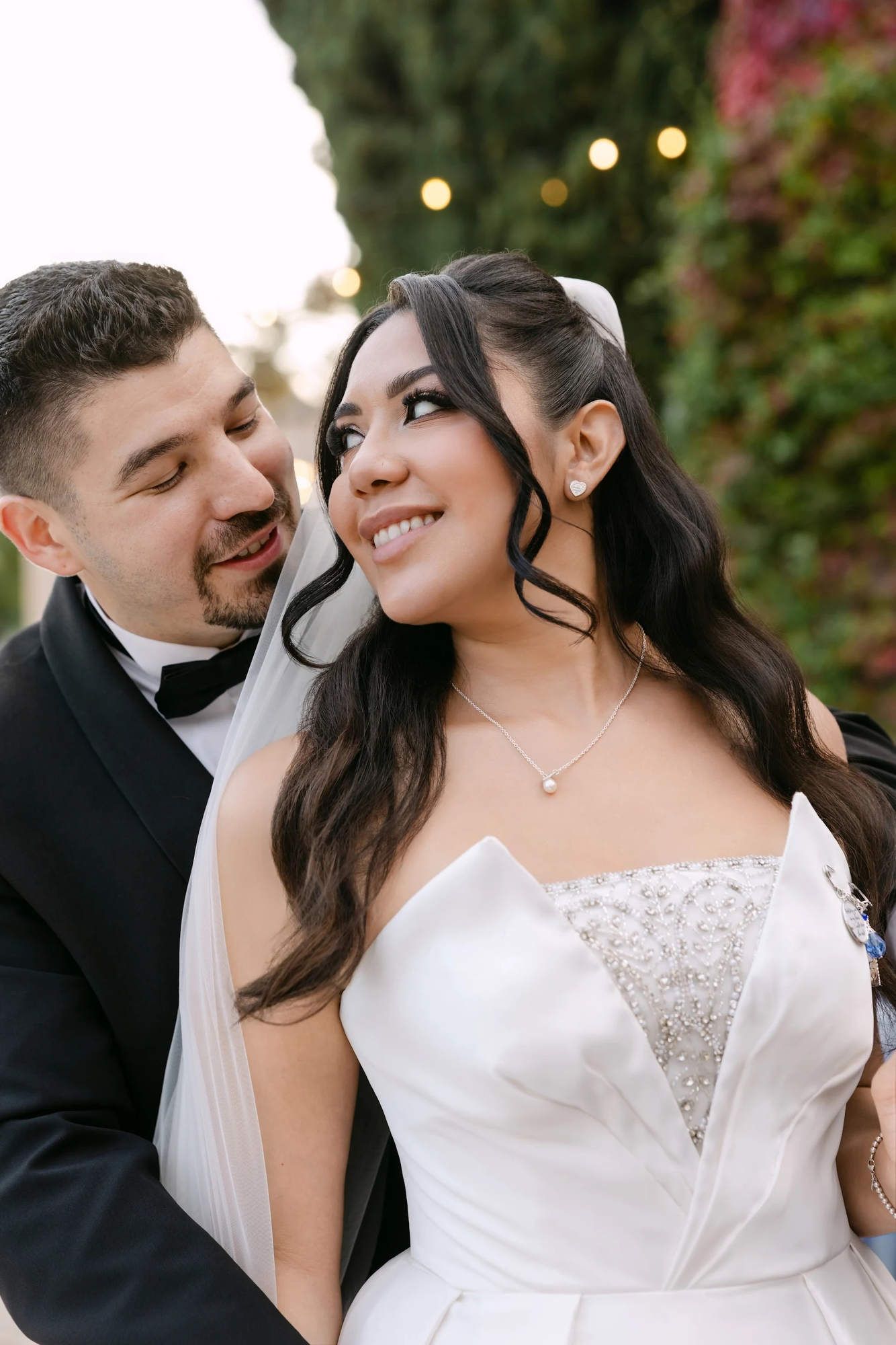 A romantic close-up of the groom hugging the bride, highlighting her professional wedding makeup and polished wave hairstyle by Larionova