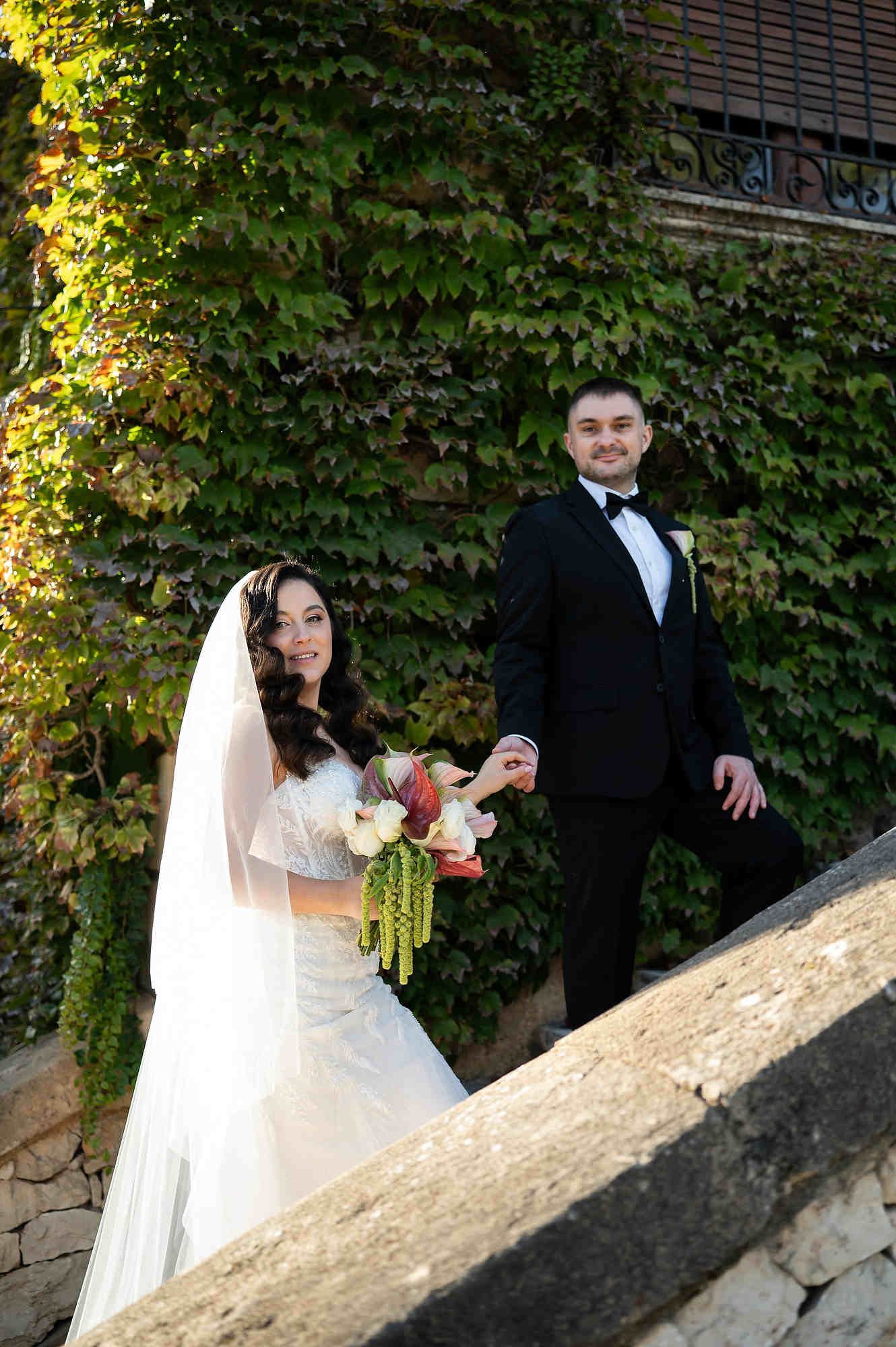 The bride and groom posing on the historic stone steps of the Casa Santonja villa, showcasing their elegant wedding attire.