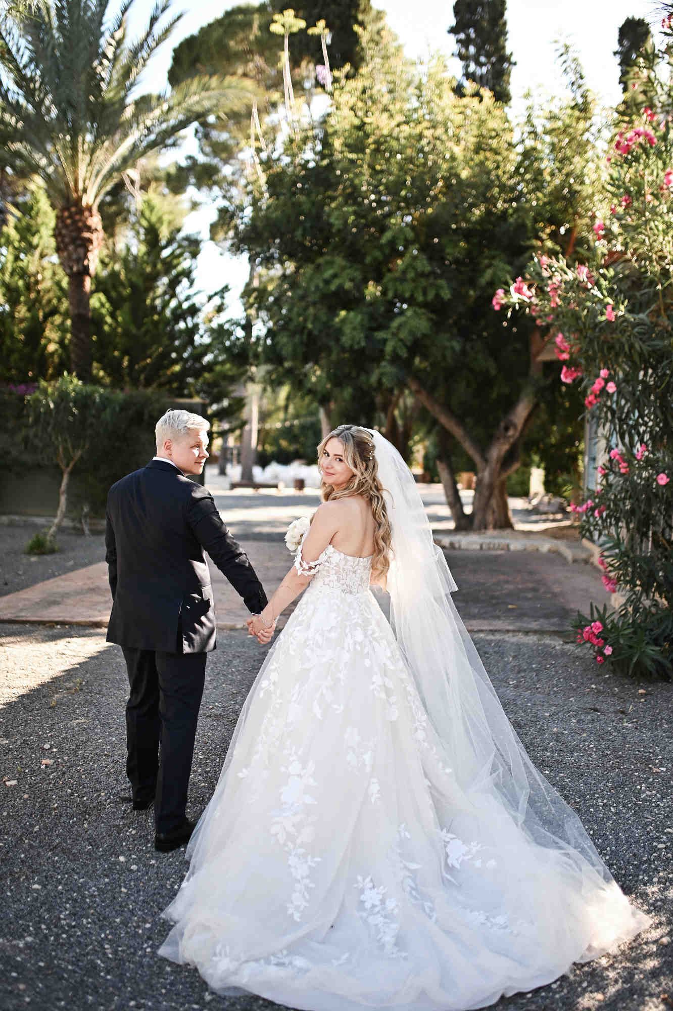 Back view of bride and groom walking at Finca El Senoret, showing her wedding dress train and elegant bridal hairstyle.