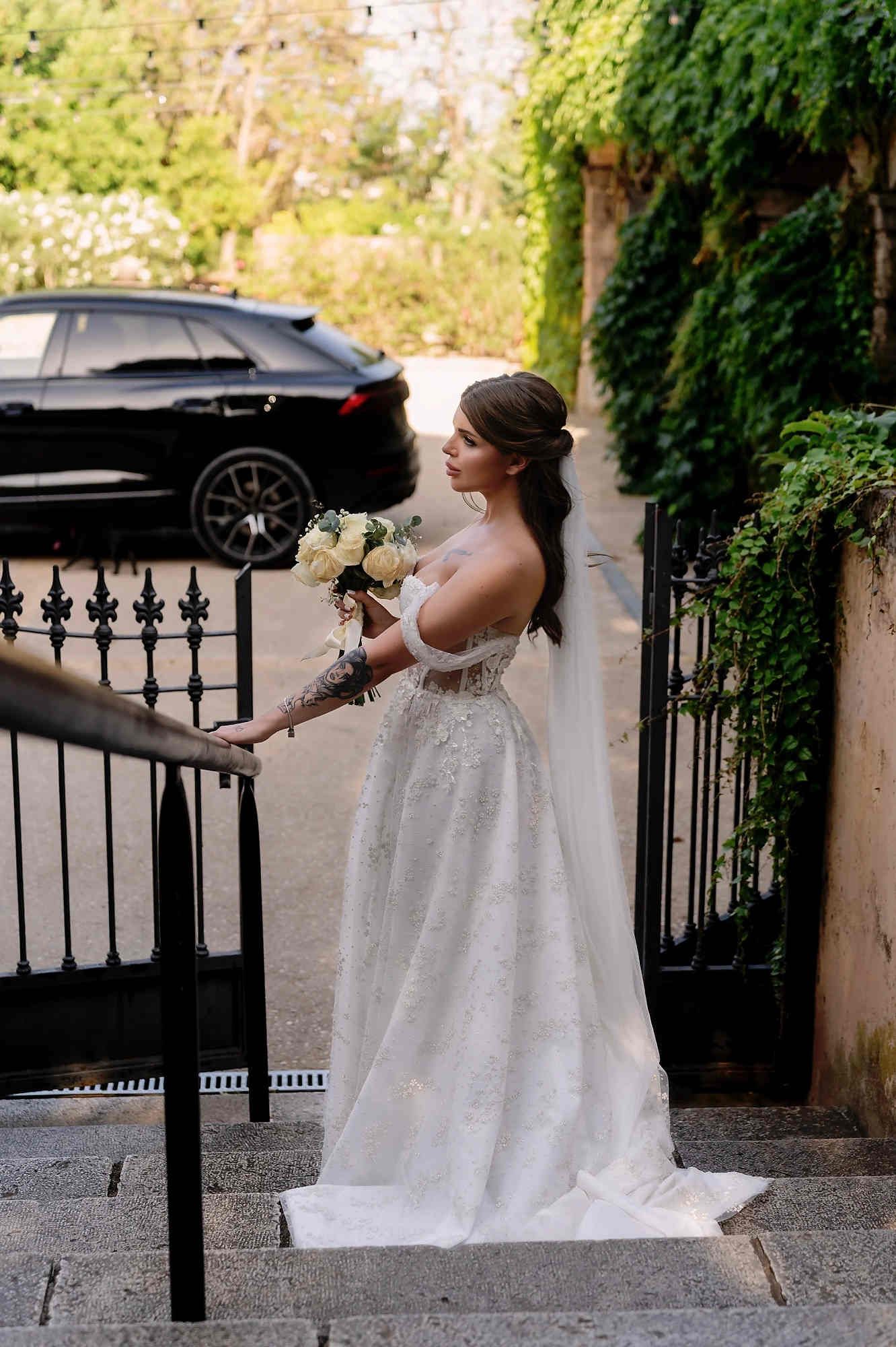 Full-length portrait of the bride at the villa exit, showcasing a sophisticated wedding hairstyle and a high-fashion bridal look.