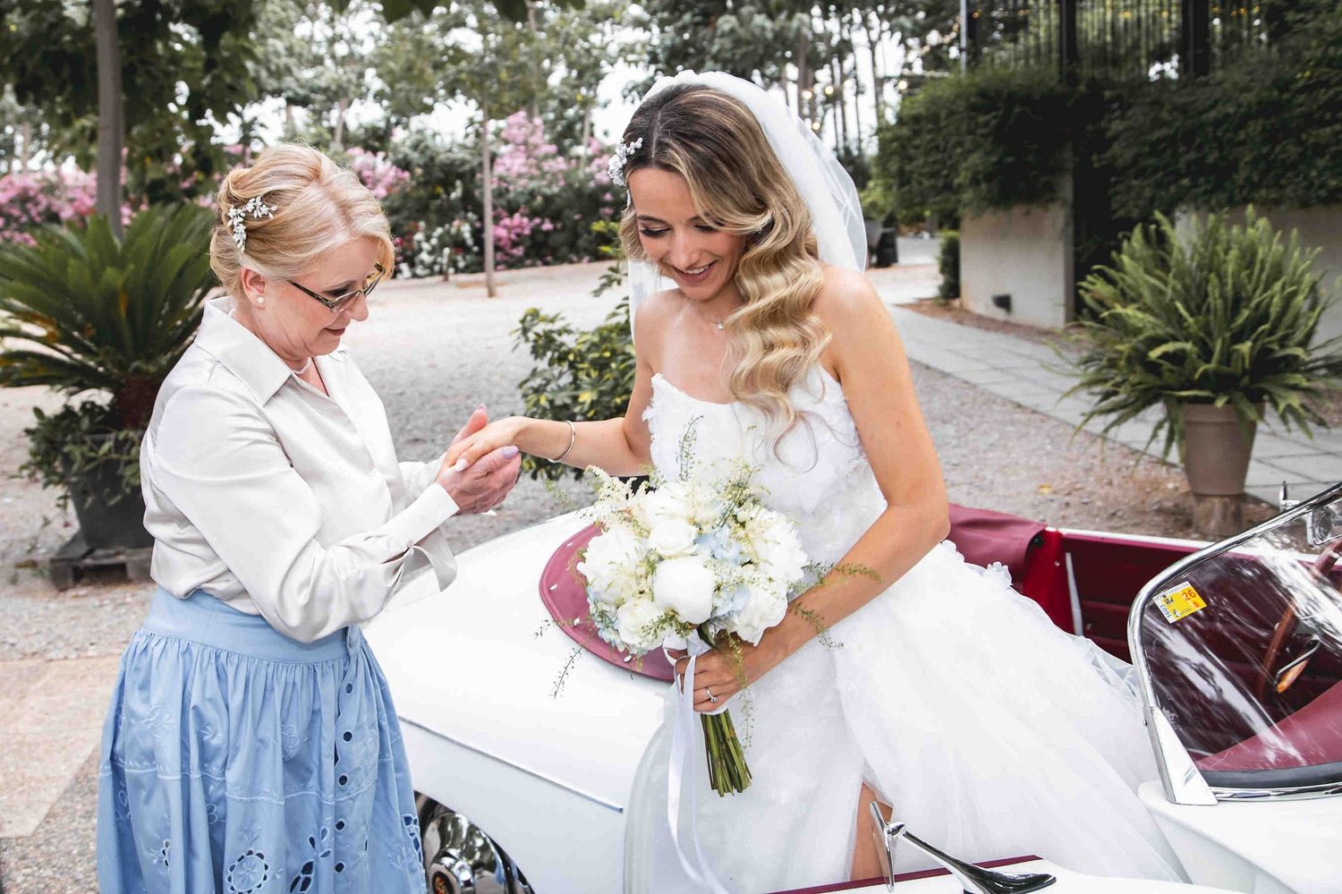 The bride stepping out of the car upon arrival at the Huerto San Rafael wedding villa, clearly showing her professional makeup and wavy hair