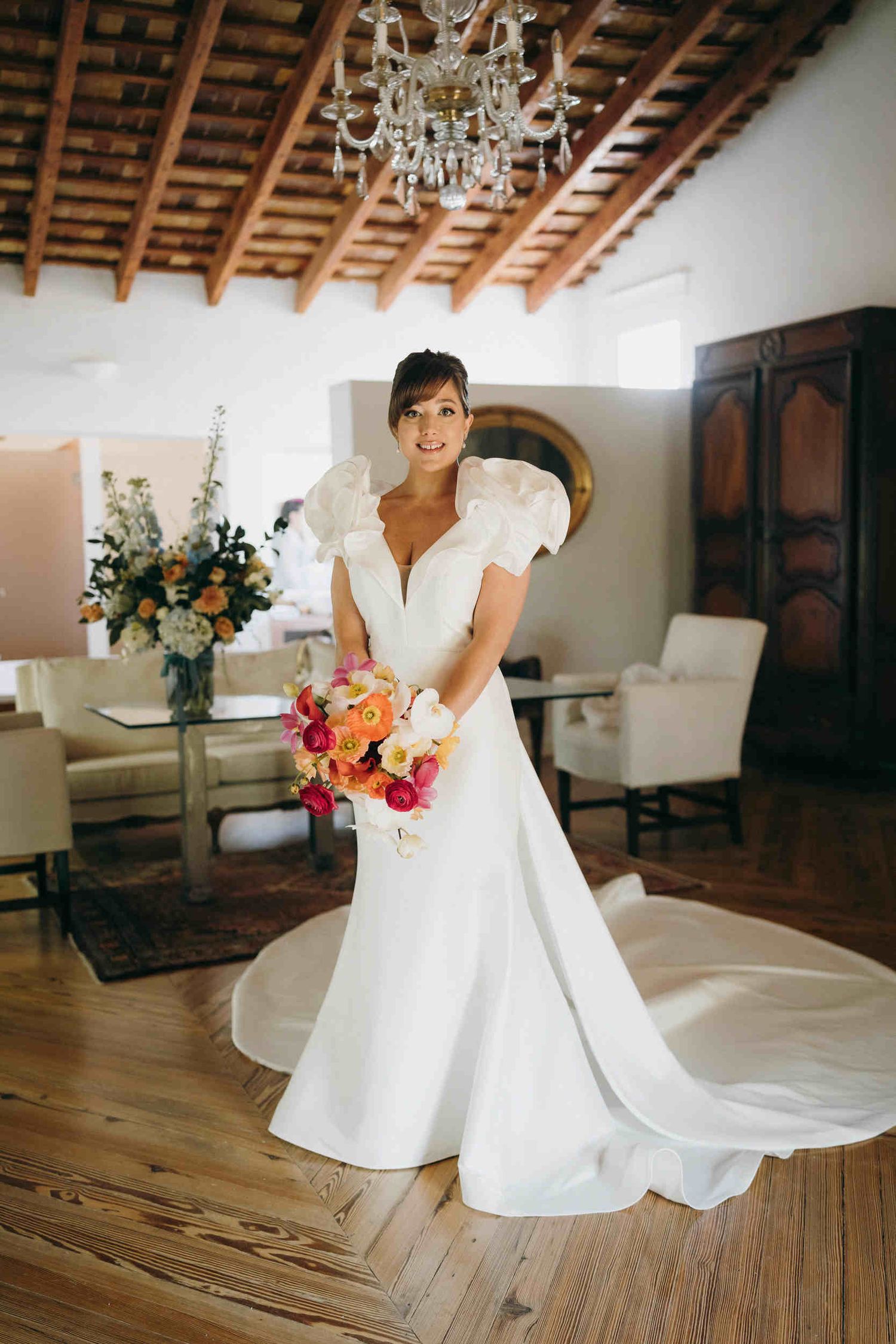 Full-length bride with professional makeup and hair styling in a luxury interior. Complete wedding look with a bouquet in a Spanish villa.
