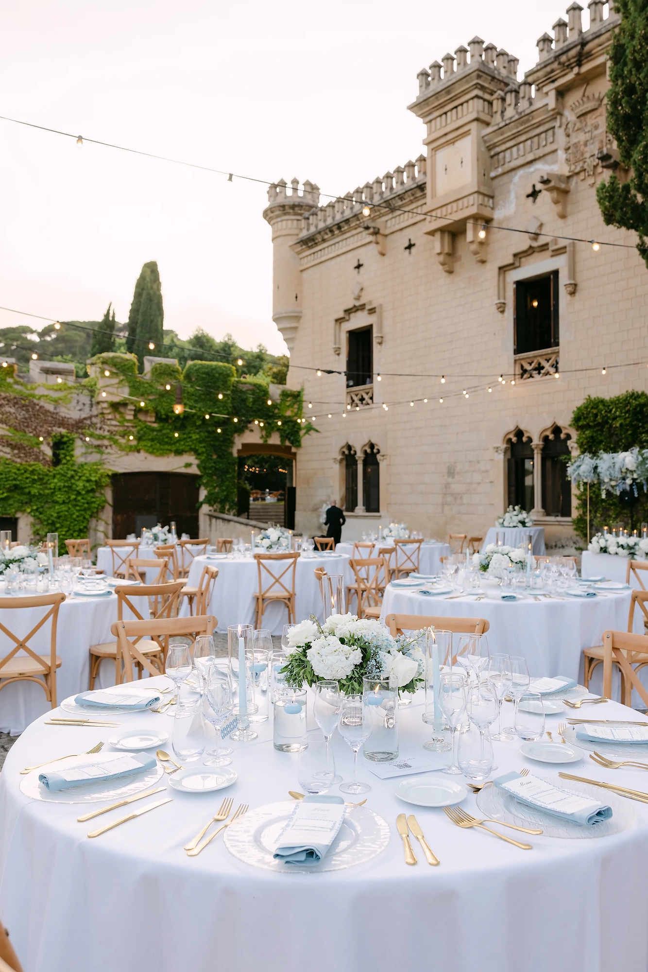 Elegant outdoor wedding banquet tables at Castell Jalpí with a stunning view of the 19th-century castle facade.