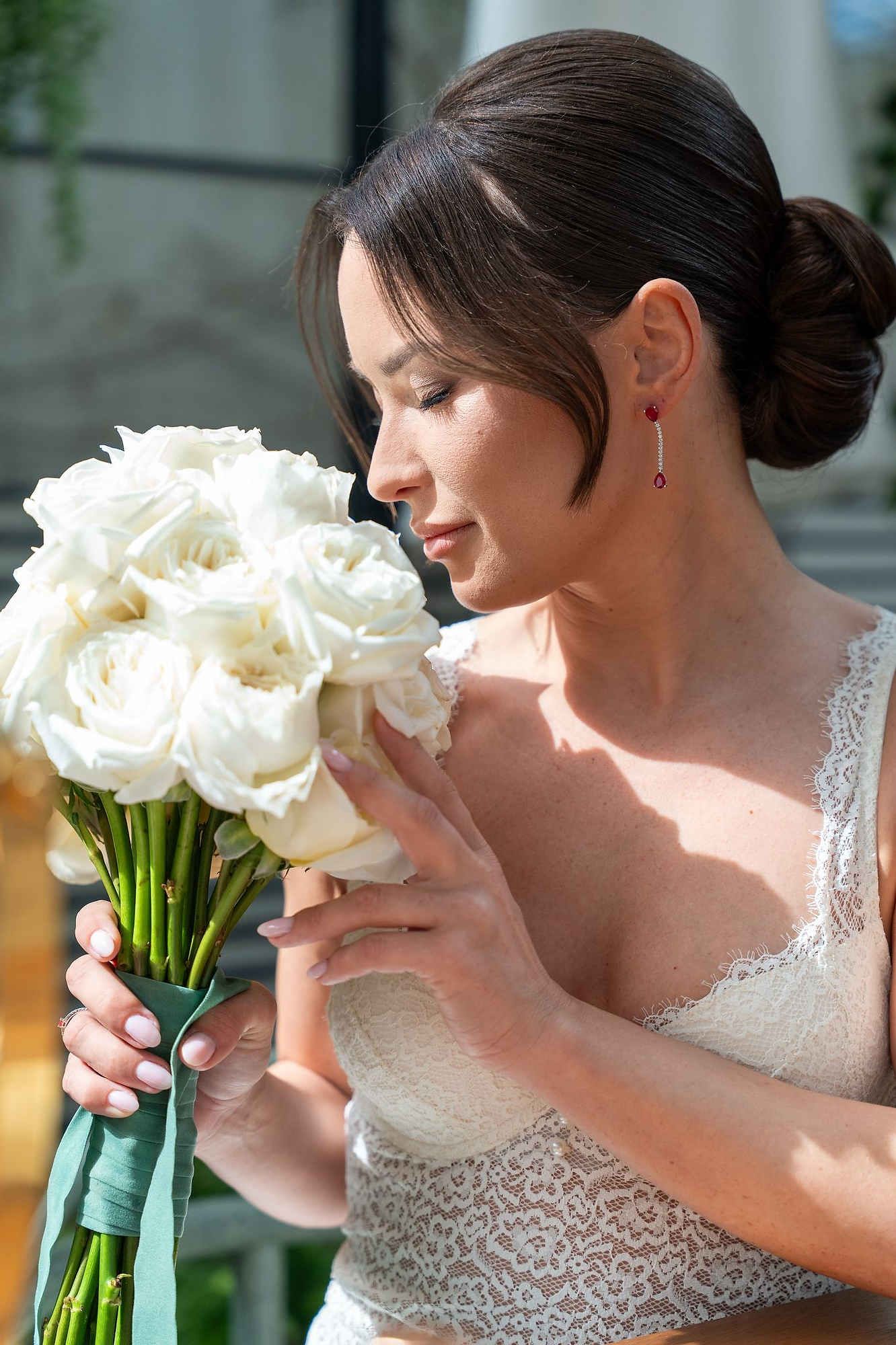 Bride with a wedding bouquet featuring sophisticated bangs and a bun hairstyle in Spain. Professional bridal hair and makeup artistry.