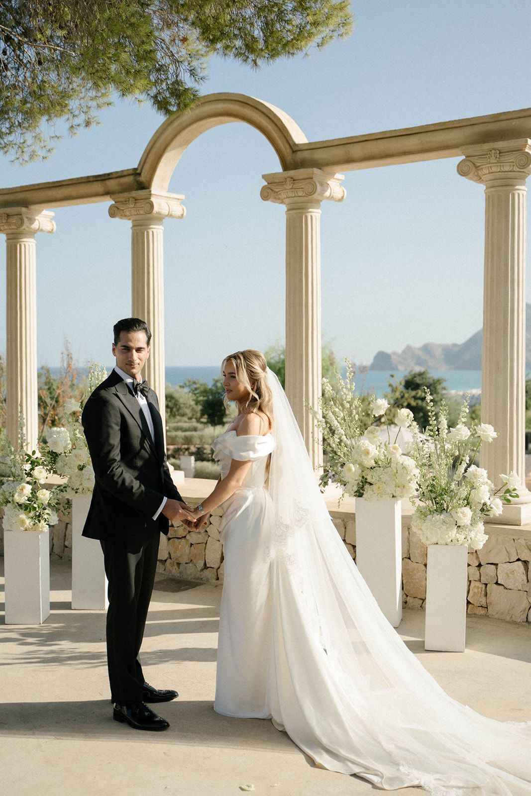 Bride and groom during their wedding ceremony standing before a beautiful floral arch at Finca Marqués de Montemolar estate in Altea.
