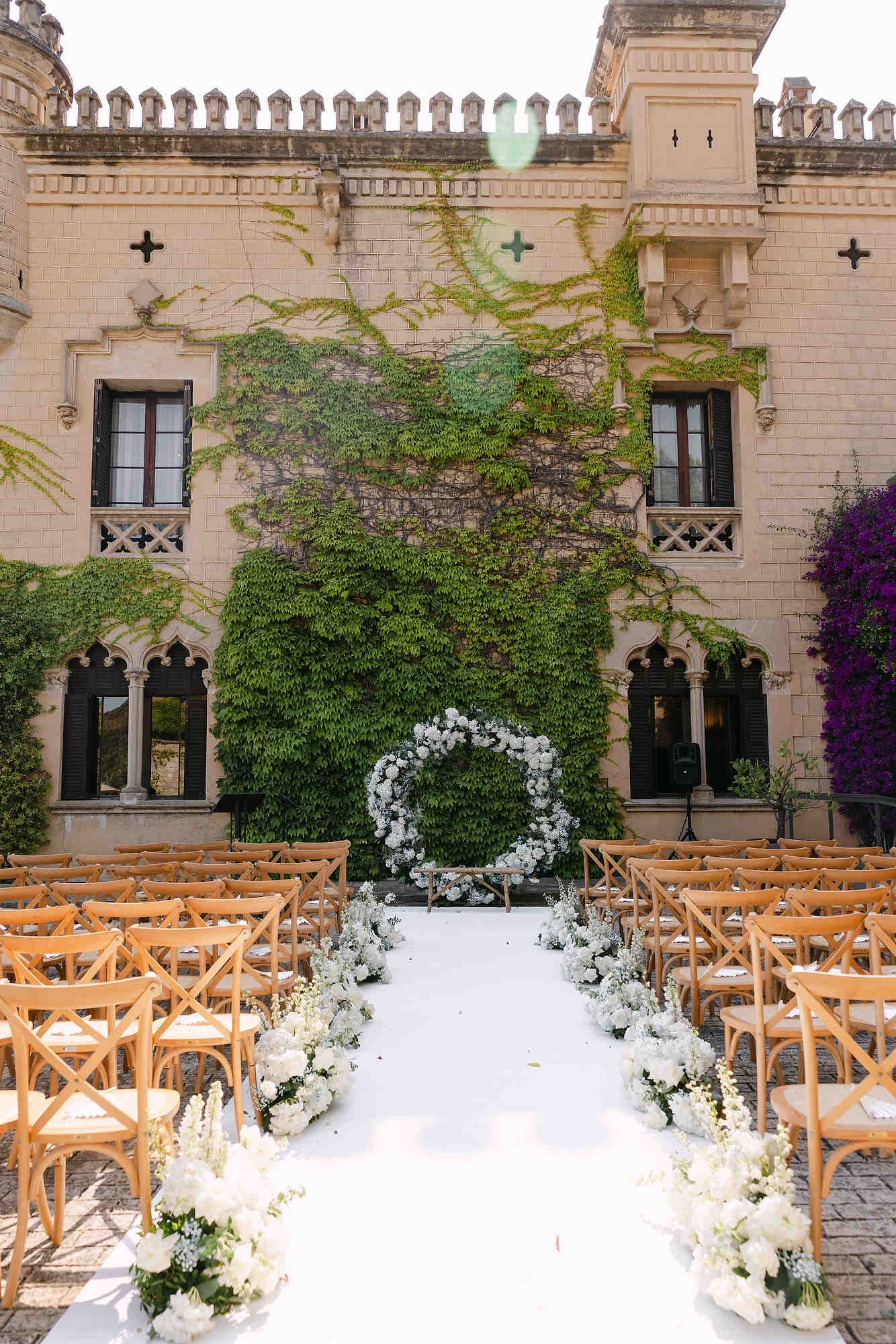 Luxury outdoor wedding ceremony at Castell Jalpí featuring elegant decor and the iconic ivy-covered stone walls