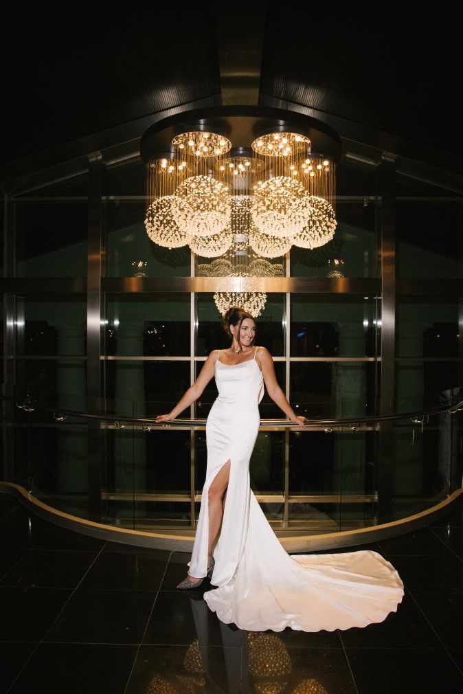 A joyful bride laughing during her wedding photoshoot in the grand interior lobby of Las Arenas Balneario Resort
