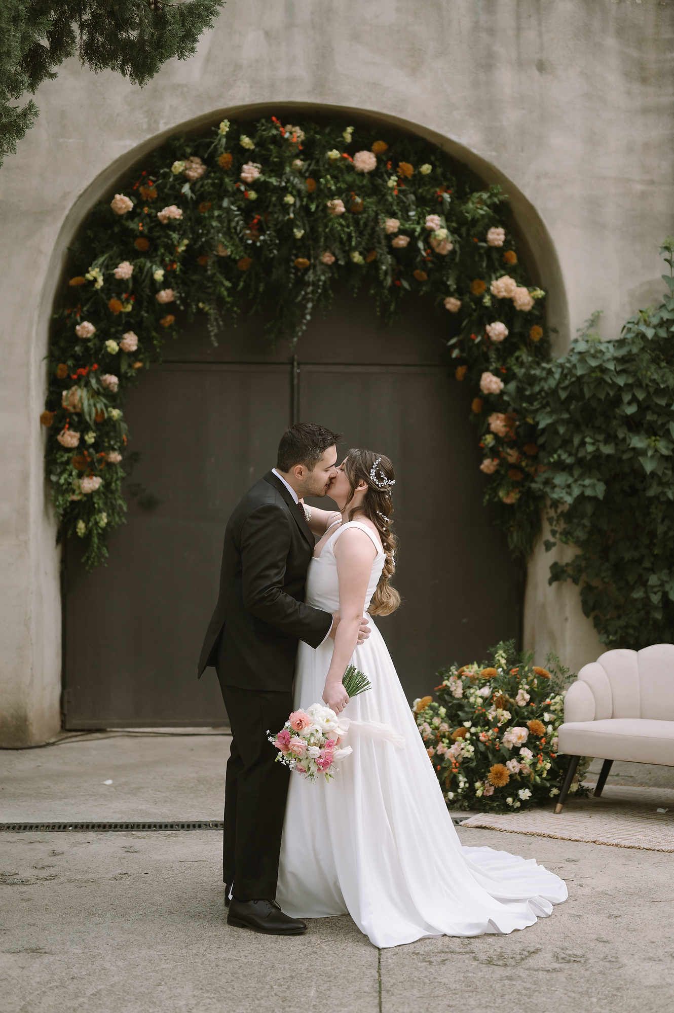 Full-length photo of a bride and groom kissing in front of the iconic historic gates of Mas d’Alzedo