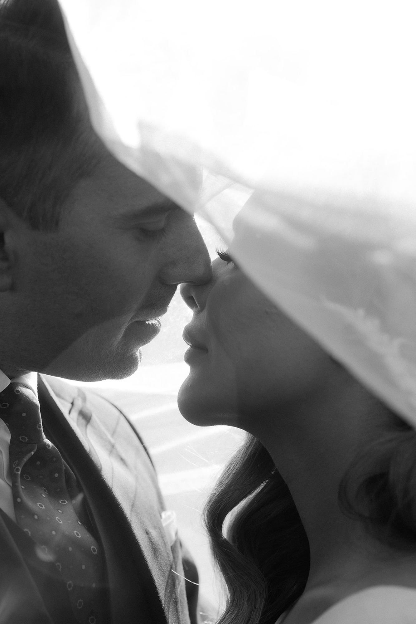 Close-up of a groom kissing his bride under a flowing veil. Romantic bridal beauty and timeless wedding moments at the villa.