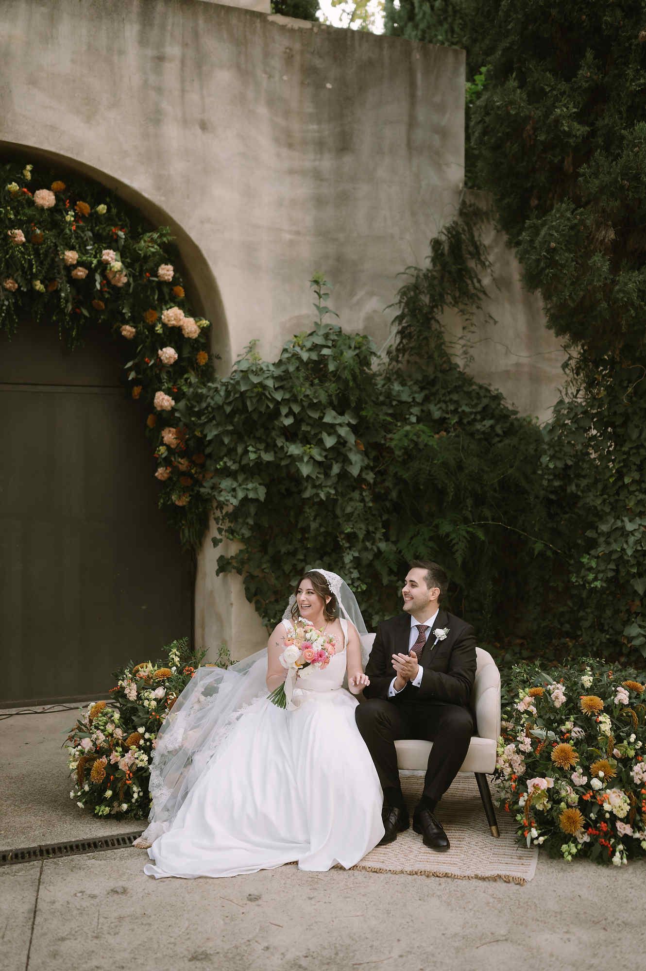 A happy bride and groom seated during their outdoor wedding ceremony at Mas d’Alzedo.
