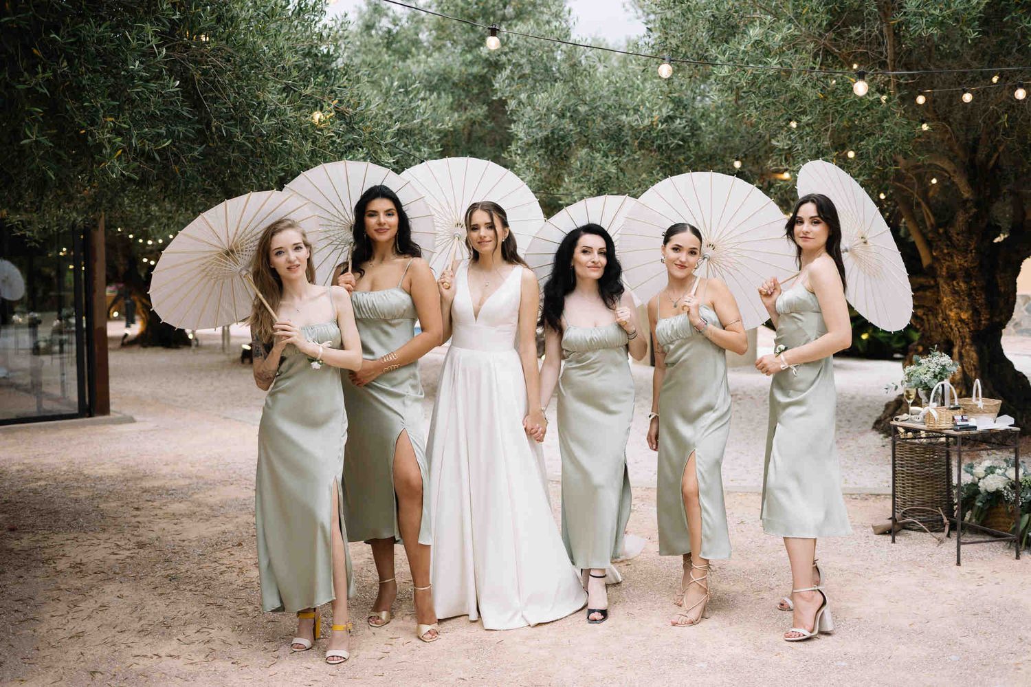 Bride and bridesmaids with sun umbrellas at Alqueria del Xúquer, showcasing professional wedding makeup and hairstyling in Valencia.