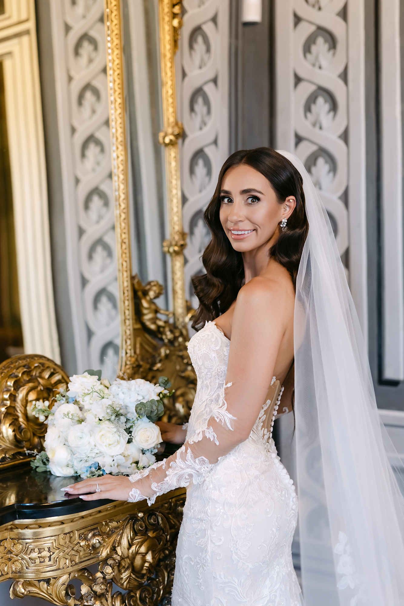 Bride in a luxury Spanish interior featuring elegant wave hairstyle with a veil. Sophisticated bridal makeup and hair styling services