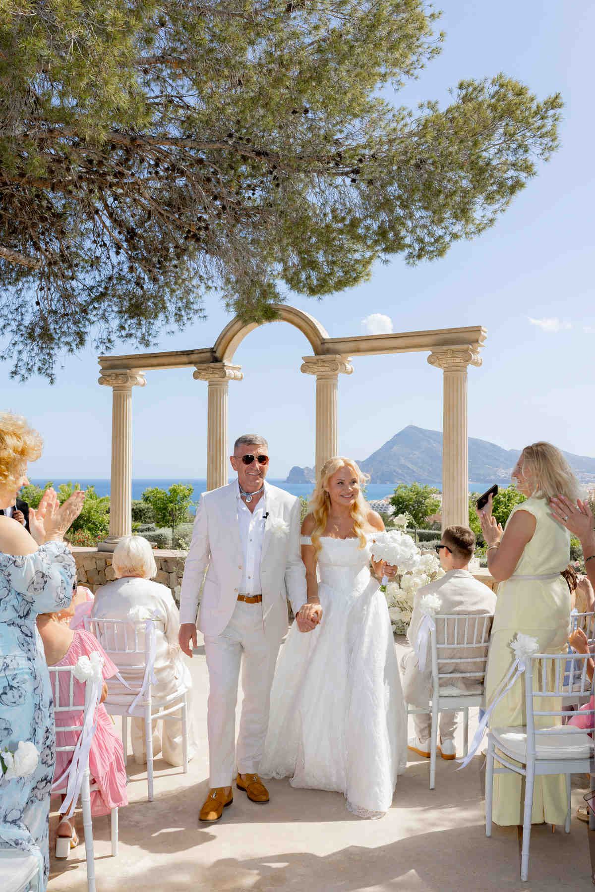 Bride and groom during their bright coastal ceremony in Altea, showcasing wind-resistant bridal hair in the sea breeze.