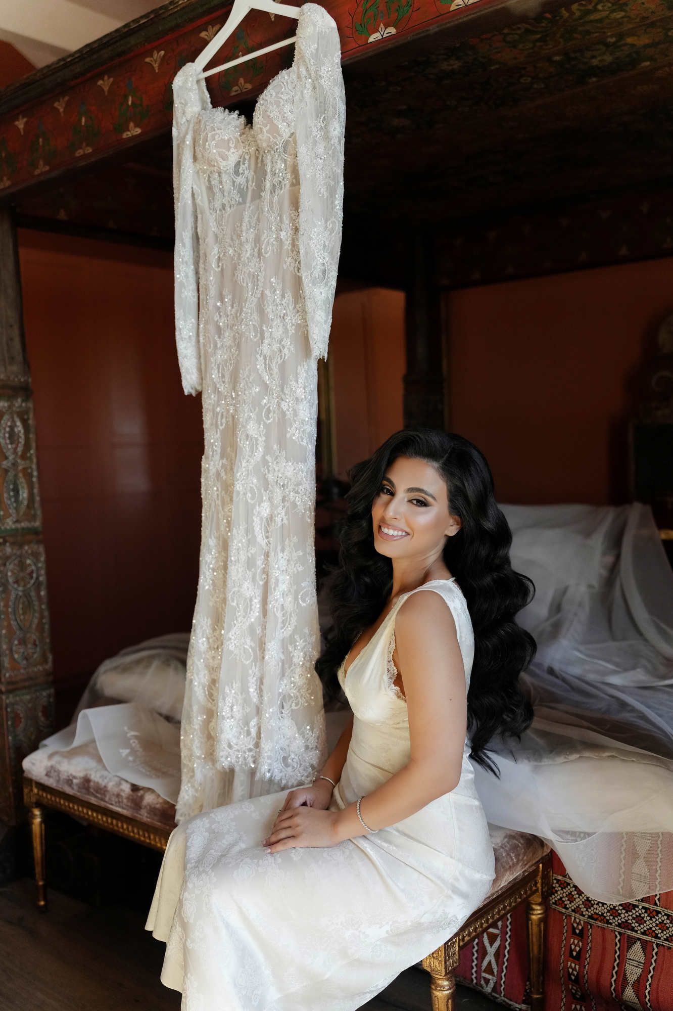 Bride with Hollywood waves and finished makeup posing near her wedding dress in a luxury suite at Gran Villa Rosa.