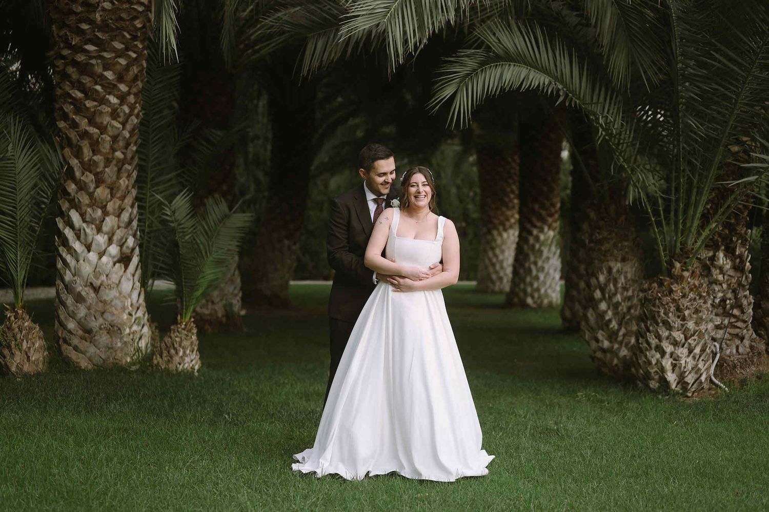 Newlyweds hugging in Mas d’Alzedo gardens. Professional bridal makeup and elegant wedding styling for a luxury Valencia celebration.