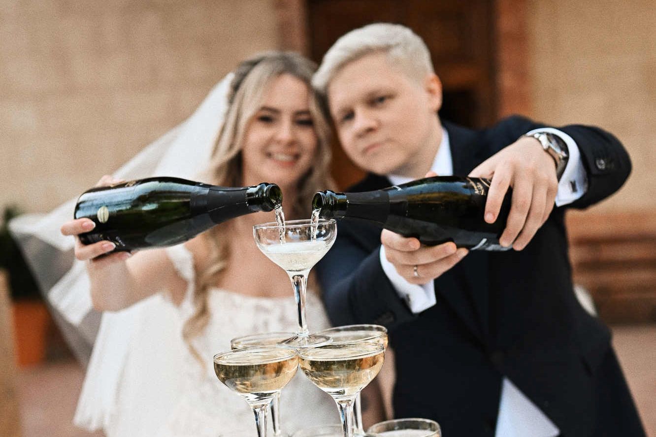 Bride and groom pouring champagne into a glass tower at their Finca El Senoret wedding reception in Alicante, Spain