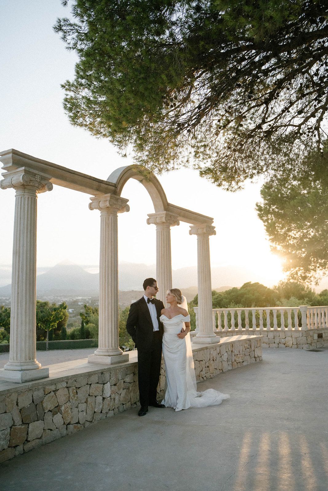 Romantic sunset photoshoot of the bride and groom by the floral arch with Mediterranean views at Finca Marqués de Montemolar, Altea.
