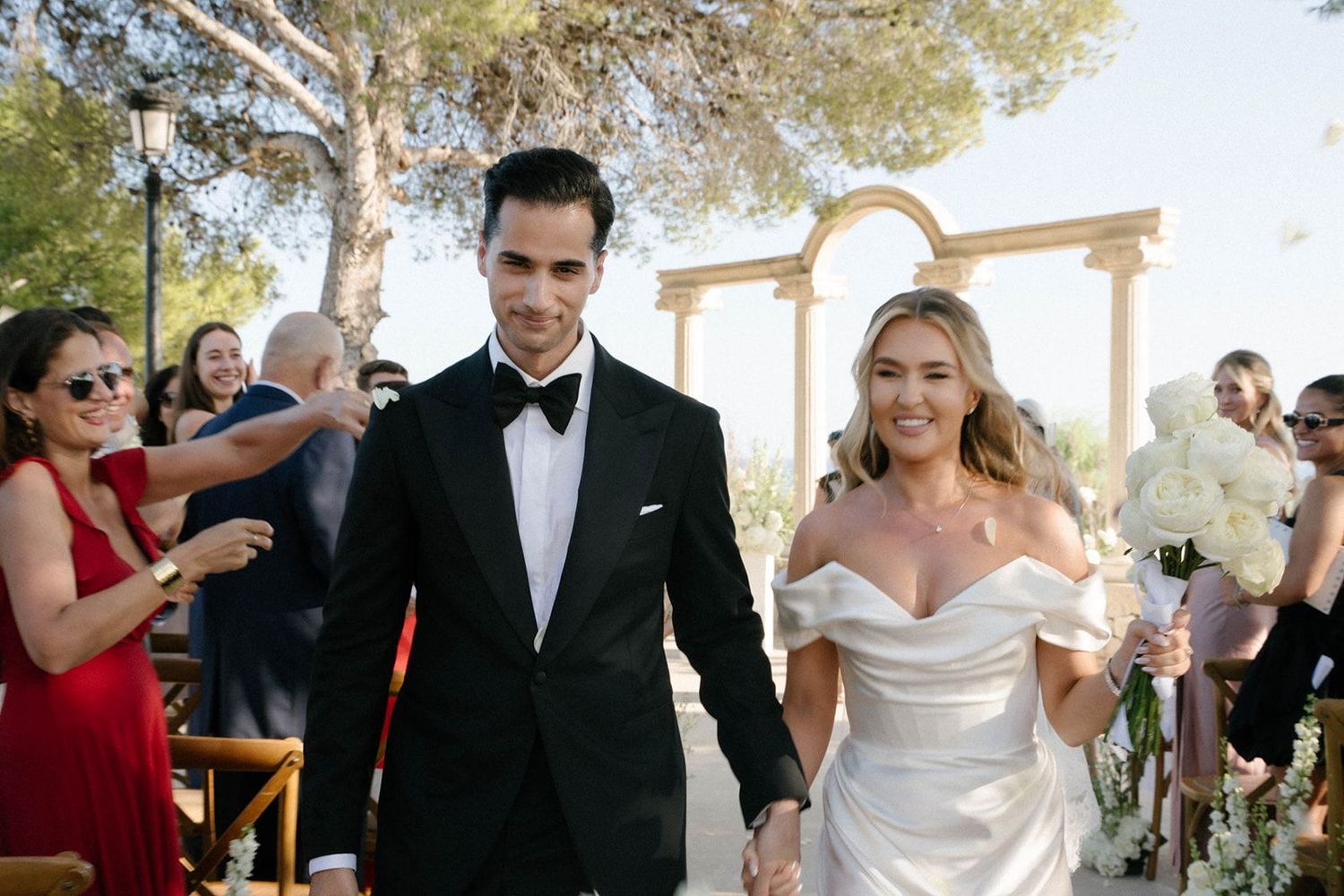 Bride and groom walking through a corridor of cheering guests during their ceremony exit at Finca Marqués de Montemolar in Altea, Spain