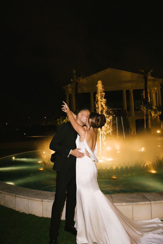 A sophisticated wedding couple posing in front of the luxury swimming pool at Hotel Las Arenas, Valencia